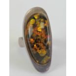 A Baltic amber cocktail ring, the large oval cabachon set in white metal approx 4cm in length,