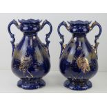 A pair of blue ground vases having gilded heron design upon, each standing 27cm high.