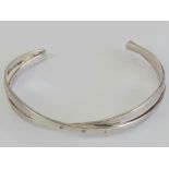 A HM silver bangle having crossover design set with three white stones, hallmarked for London, 17.