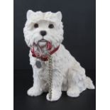 A figurine of a Westie with collar holdi