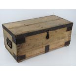 A vintage pine lidded trunk having iron bracing and end handles, measuring 62 x 31 x 26cm.