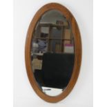 An Edwardian oval bevelled edge wall mirror, mahogany frame strung with boxwood and ebony in a