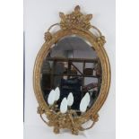 A good early 20thC oval gilt wall mirror having triple sconce under and wired for electricity.