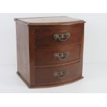 A mahogany table top barrel fronted chest of three jewellery drawers, pediment deficient.