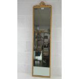 A c1960s gilded full length wall mirror with pierced ribbon crest over, 135 x 34cm.