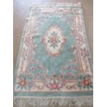 A green ground woollen rug having pink and cream floral pattern measuring 196 x 120cm.