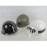 Three helmets including; black painted helmet, white painted IMP helmet and another.