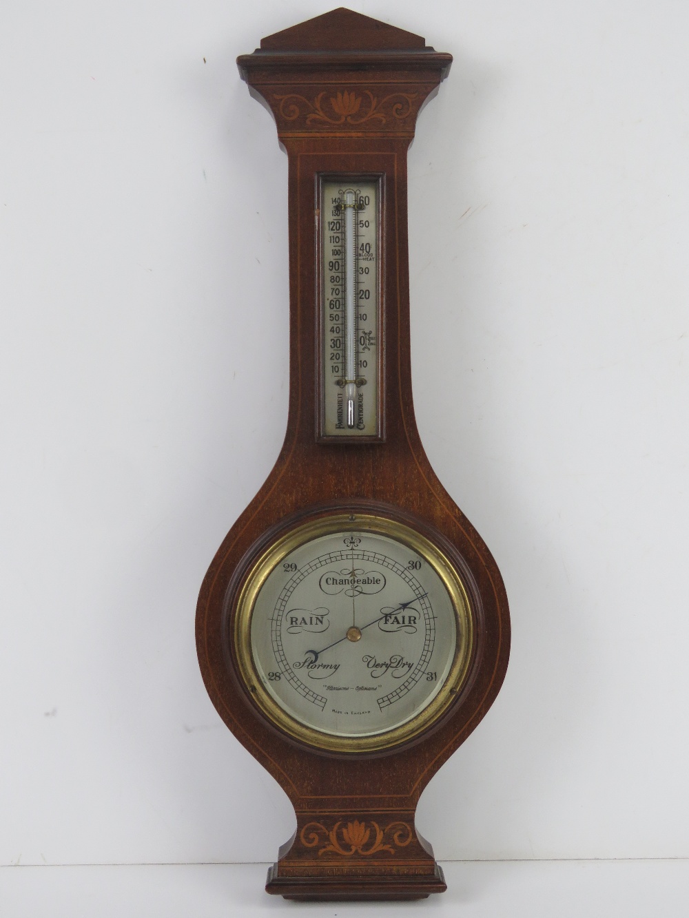 An Edwardian mahogany and inlaid wall barometer having thermometer over aneroid barometer marked