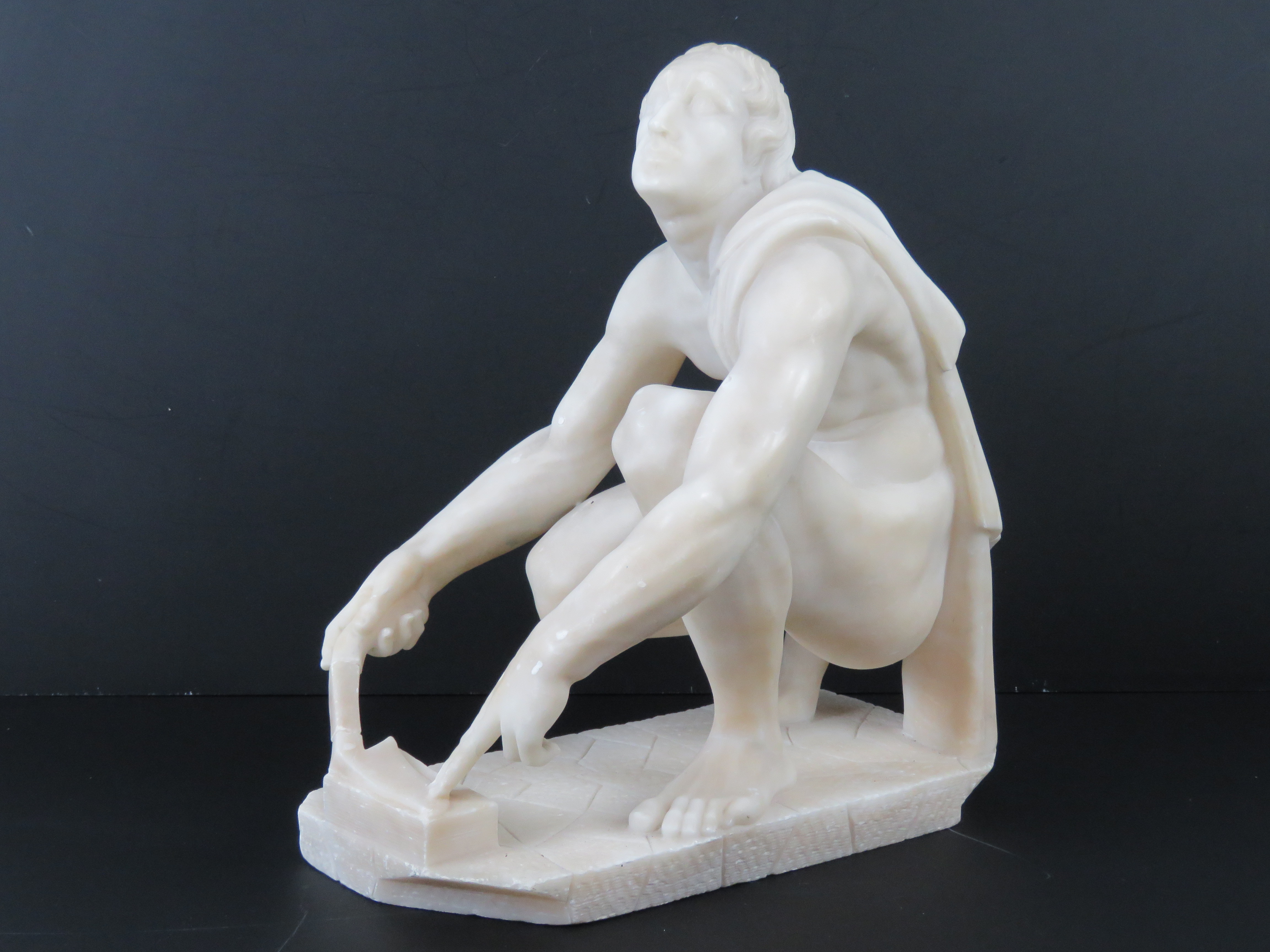 A well carved alabaster sculpture; Grecian school, kneeling man.