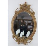 A good early 20thC oval gilt wall mirror having triple sconce under and wired for electricity.