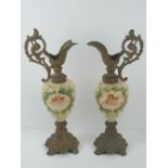 A pair of decorative ceramic 'ewers' having transfer printed cherubs upon and further hand painted