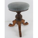 A piano stool having circular padded seat and triform base, height adjustable,