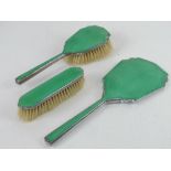 An Art Deco dressing table set having green guilloche enamel back comprising hairbrush,
