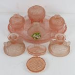 An early 20thC dressing table set in peach coloured glass comprising trays, storage pots,