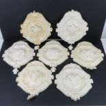 A set of seven clay wall decorations, each having rams head to centre, a/f, each 30cm wide.