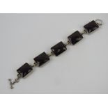 A five panel bracelet each set with faceted garnet coloured paste, no apparent hallmarks,