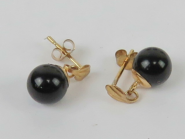 A pair of yellow metal and onyx earrings, no apparent hallmarks, with butterfly backs.