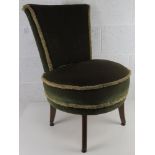 A fireside chair upholstered in green velvet.
