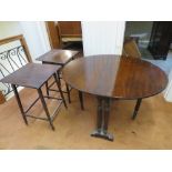 A mahogany drop leaf oval table raised over reeded columns and having pull out leaves,
