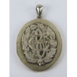 A large vintage white metal locket having BCH monogram to centre of leafy wreath, 5.4cm in length.