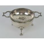An HM silver tea strainer and bowl raised over three feet, hallmarked Birmingham 1931, 47.1g / 1.