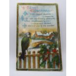 A vintage Christmas postcard featuring bird upon fence with snow covered bridge and building