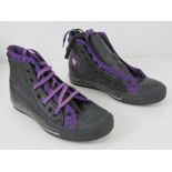 A pair of black leather Converse All Star trainers with two pairs of laces in black and purple,