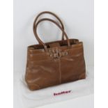 A tan leather handbag having dust cover