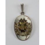 A silver pendant having central oval cut