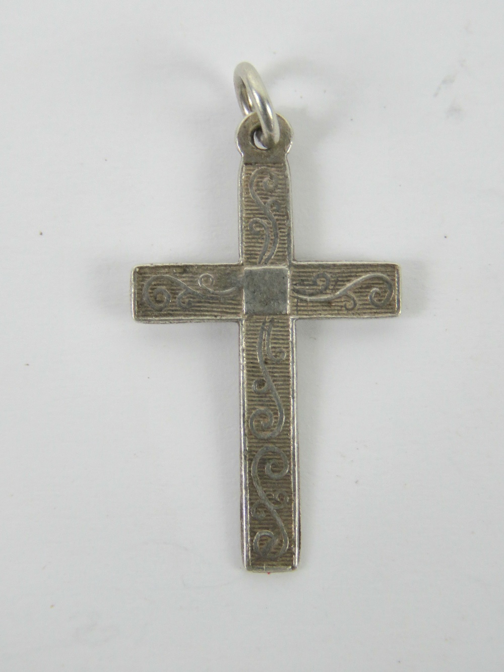 A silver crucifix pendant having scrolli