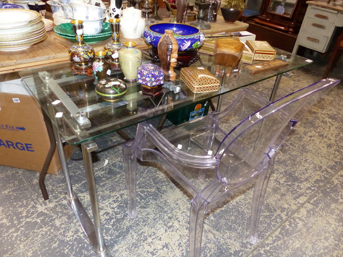 A CHROME AND GLASS DESK AND A PERSPEX ARM CHAIR.