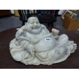 A CHINESE GREY GREEN SOAPSTONE CARVING OF BUDAI SMILING AS HE RECLINES ON HIS SACK OF POSSESSIONS, A