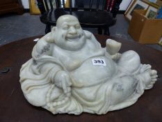 A CHINESE GREY GREEN SOAPSTONE CARVING OF BUDAI SMILING AS HE RECLINES ON HIS SACK OF POSSESSIONS, A