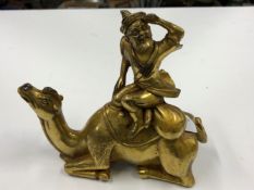 A GILT BRONZE EASTERN FIGURE SEATED ON RECUMBENT CAMEL.