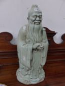 A CELADON GREEN GLAZED CHINESE FIGURE.