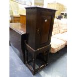 AN ANTIQUE OAK PANEL DOOR CABINET ON STAND.