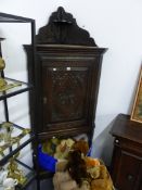 AN ANTIQUE CARVED OAK CORNER CABINET ON STAND.