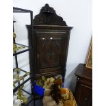 AN ANTIQUE CARVED OAK CORNER CABINET ON STAND.