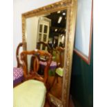 A LARGE BEVELLED MIRROR WITH FLORAL GILT FRAME 136 X 107 CM