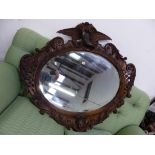 AN ANTIQUE CARVED WALNUT FRAMED MIRROR WITH EAGLE SURMOUNT.