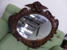 AN ANTIQUE CARVED WALNUT FRAMED MIRROR WITH EAGLE SURMOUNT.