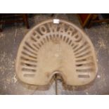 A HOWARD CAST IRON TRACTOR SEAT ON STOOL SUPPORT.