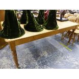 AN ANTIQUE PINE BREAKFAST TABLE WITH LATER BRASS CASTORS.