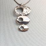 A SILVER HAMMERED AND POLISH FINISHED GRADUATING PENDANT SUSPENDED ON A SILVER SNAKE CHAIN.