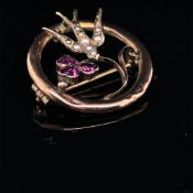 A VICTORIAN 9ct GOLD LOVE TOKEN BROOCH. THE SWALLOW SET WITH SEED PEARLS HOLDING A PINK GEMSET
