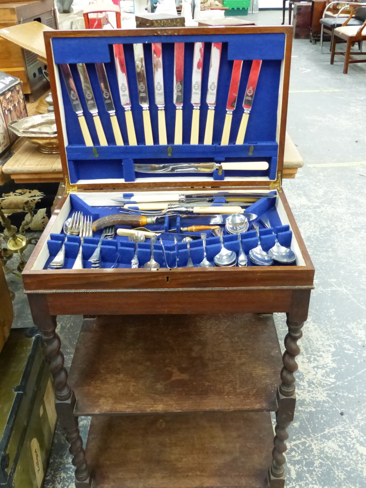 A PART SET PLATED CANTEEN OF CUTLERY ON A FITTED OAK TWO TIER STAND.