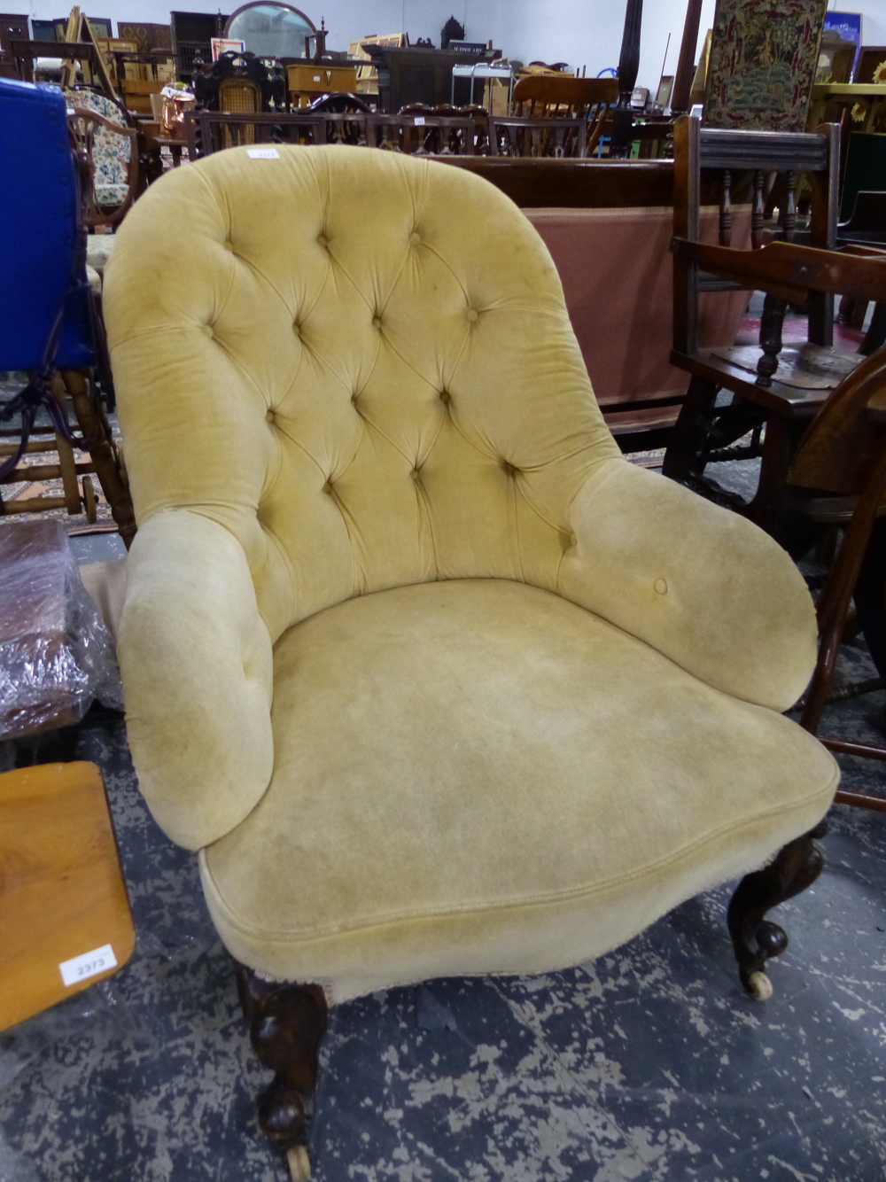 A VICTORIAN BUTTON BACK ARMCHAIR ON CARVED FORELEGS.