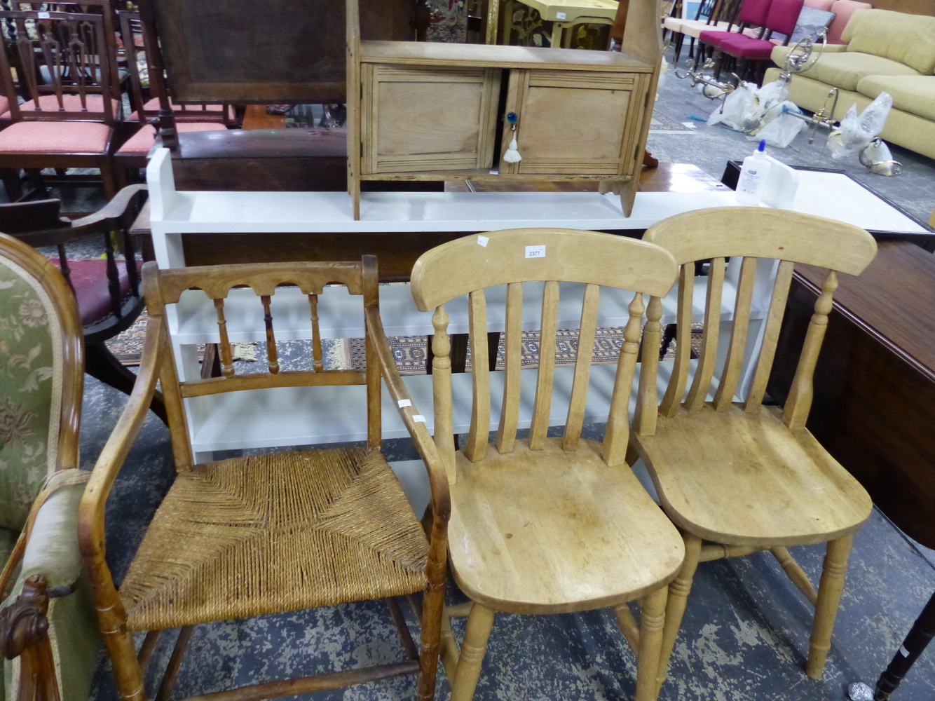 AN ANTIQUE RUSH SEAT ARMCHAIR, TWO KITCHEN CHAIRS, PAINTED SHELVES AND SMALL WALL CABINET.