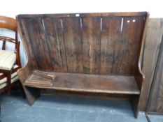 AN 18th C. PINE SETTLE, THE CLEATED VERTICAL PLANK BACK RUNNING BELOW THE SEAT TO FORM FEET, THE