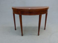 A GEORGE III MAHOGANY DEMI LUNE GAMES TABLE, THE SATIN WOOD CROSS BANDED TOP OPENING ON SINGLE GATE,